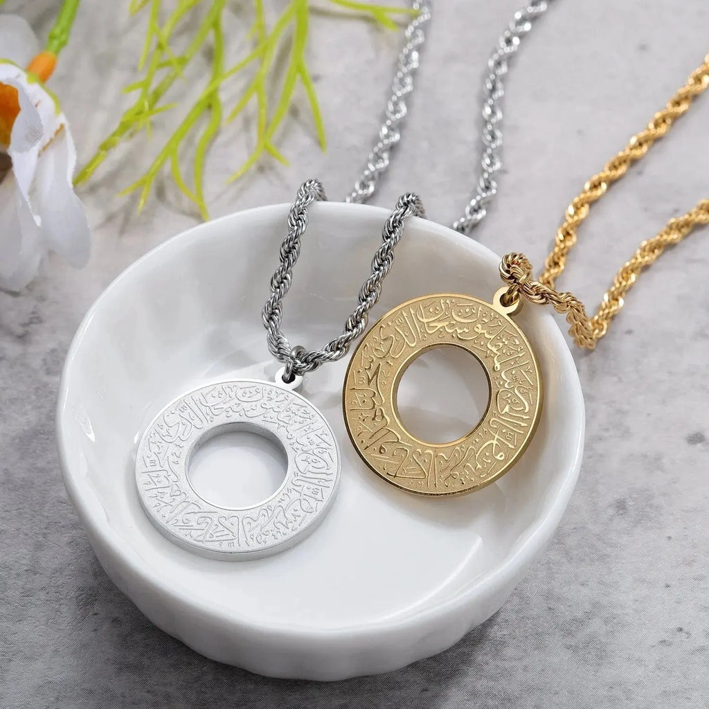 Silver and gold circular pendants with Arabic calligraphy on twisted chains in a white bowl.