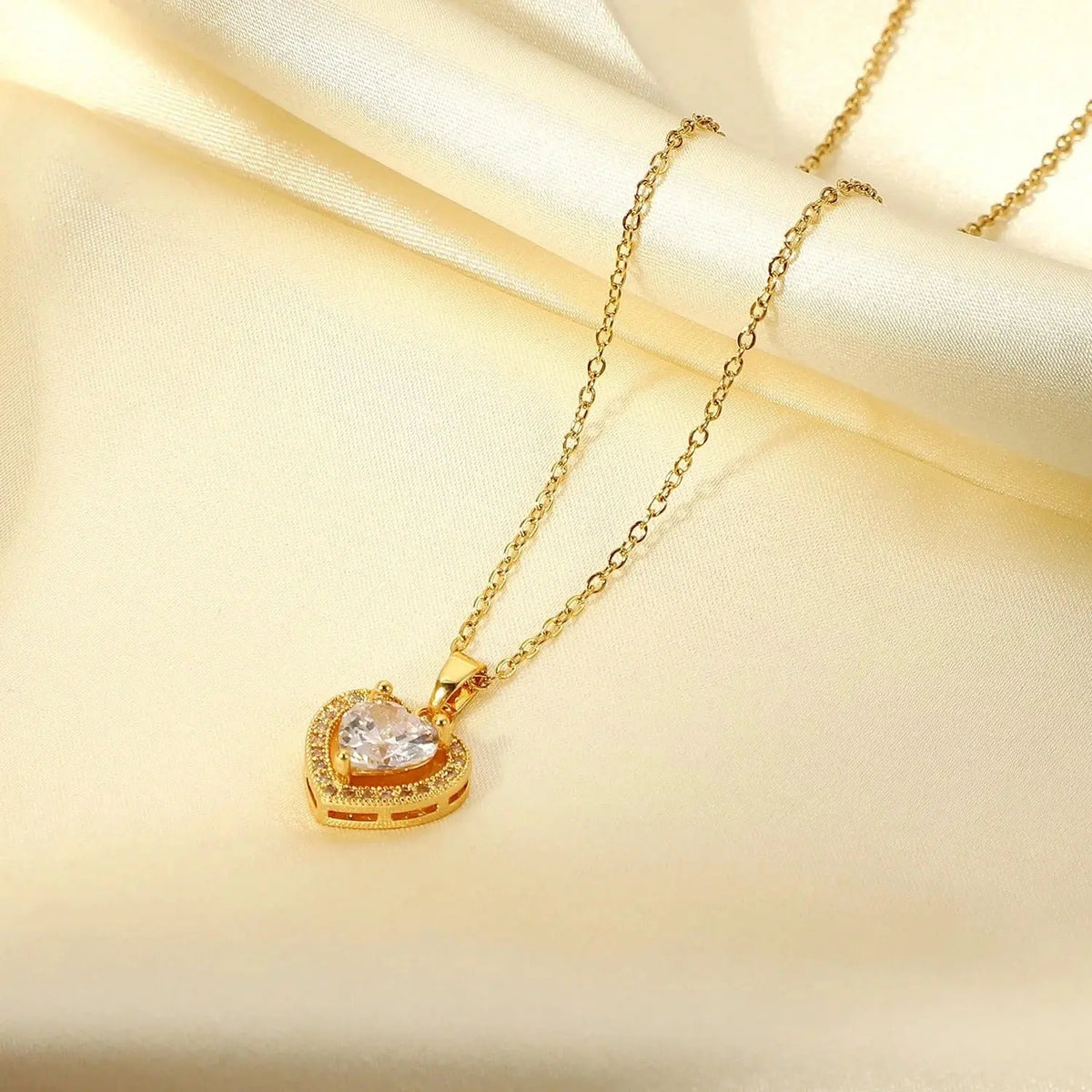 Gold heart-shaped pendant necklace with sparkling crystals on cream silk fabric
