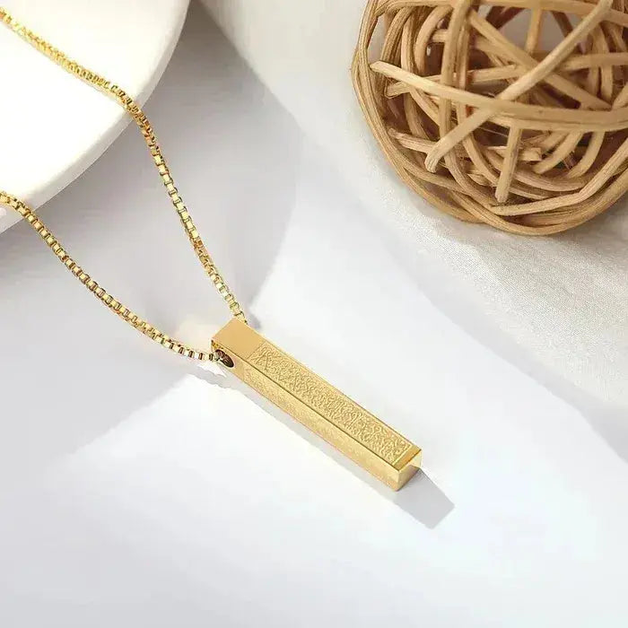Gold bar pendant necklace with textured finish on a white background