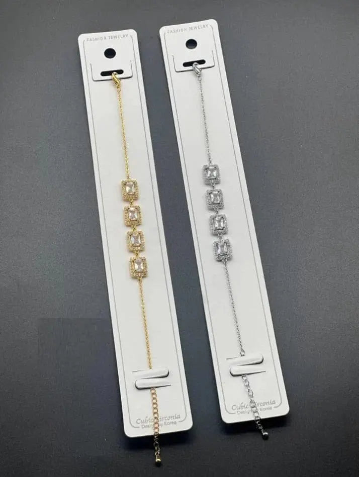 Gold and silver cubic zirconia bracelets on white display cards.