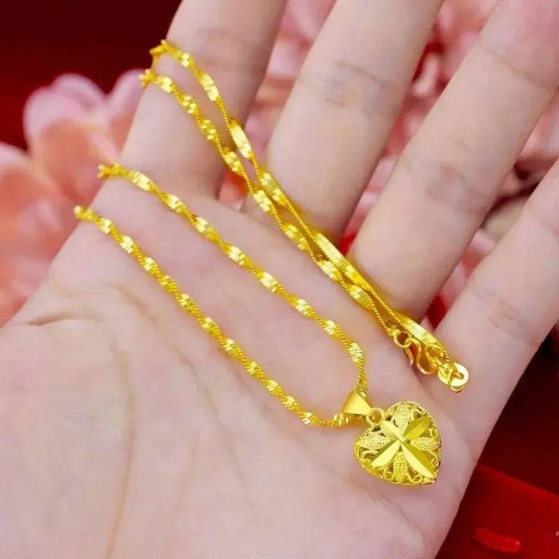Gold heart pendant necklace held in a hand