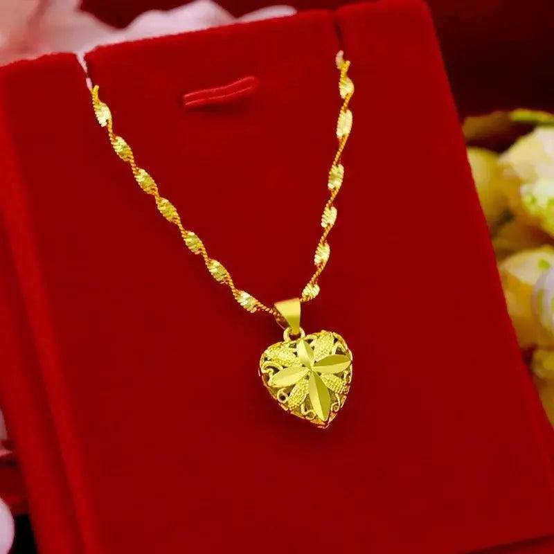 Gold heart-shaped pendant necklace with floral engraving on a red velvet box